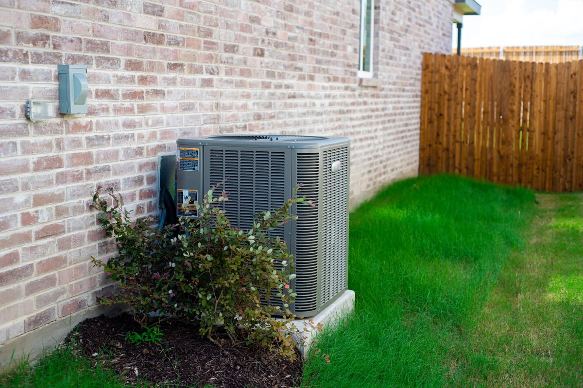 Outdoor HVAC unit installed alongside a modern brick home with green grass landscaping, USA